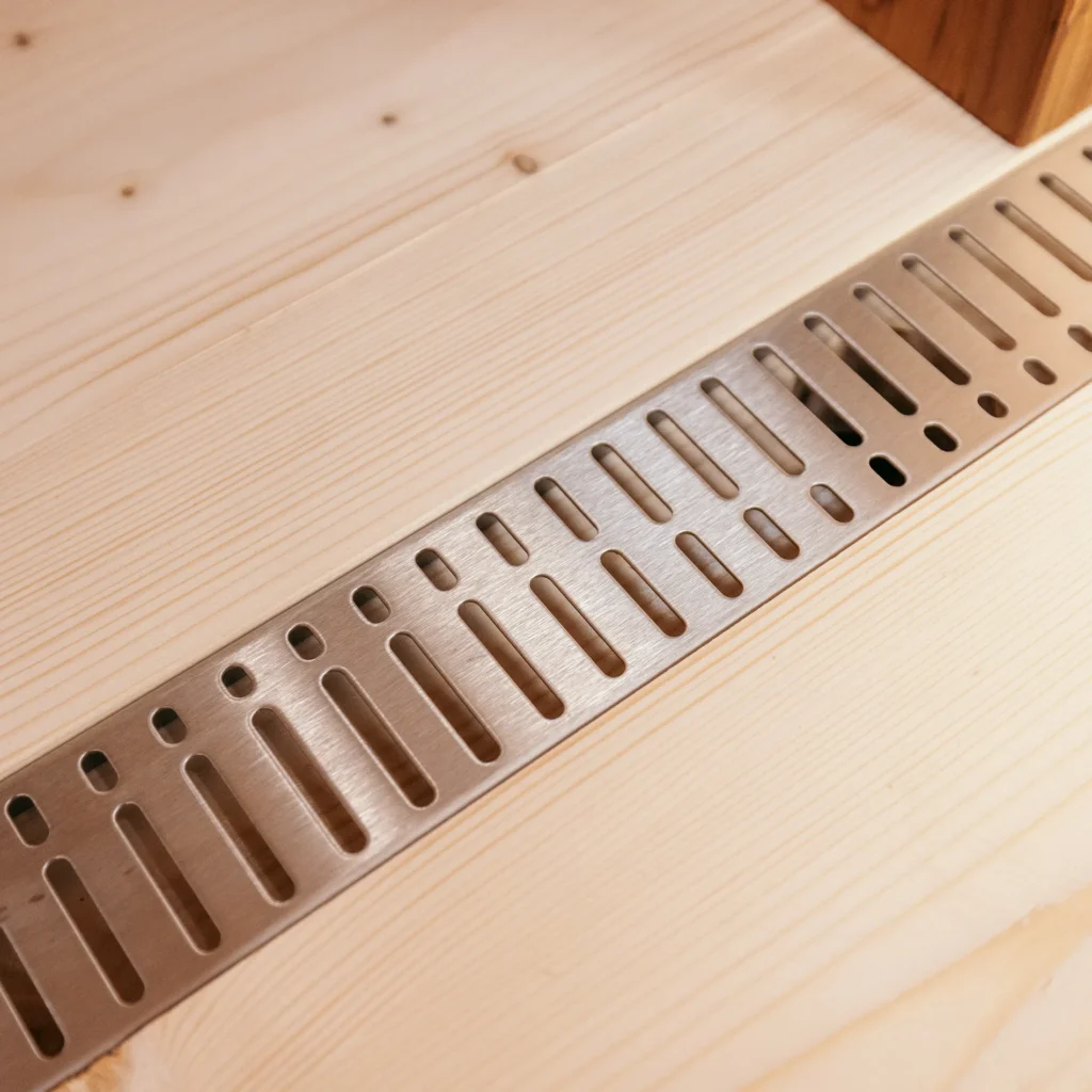 Stainless steel drain cover in the natural spruce floor of the OneEighty Small Outdoor sauna