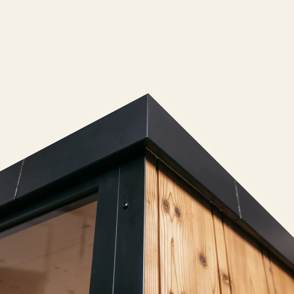 Black aluminium roof verge over the natural thermo spruce wall of the OneEighty Small Outdoor sauna